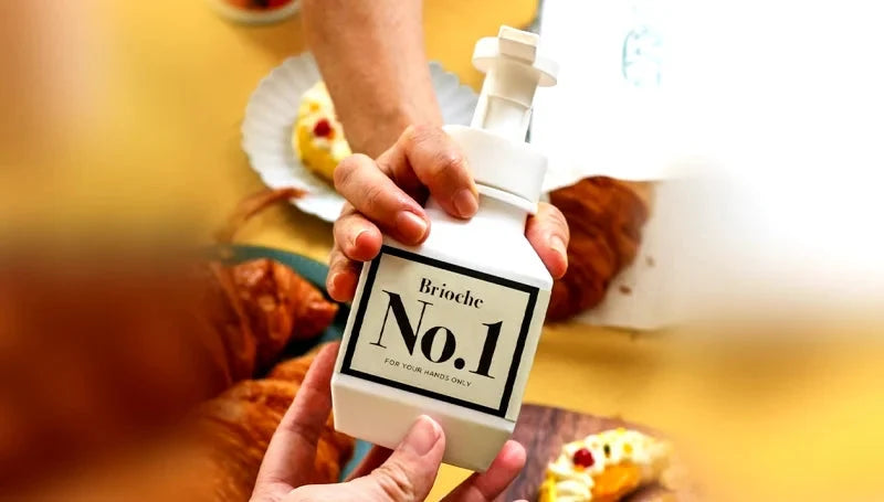 A hand holding Brioche No. 1 hand wash beside pastries