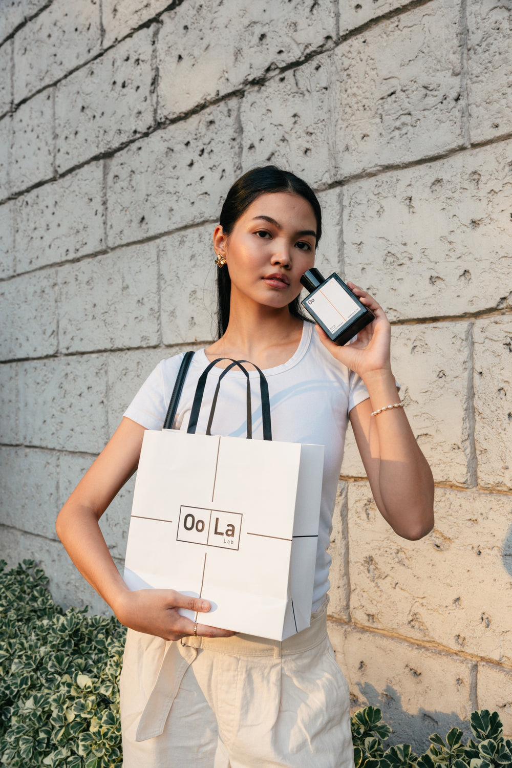 A woman holding perfume 572 Confidence and an Oo La Lab bag